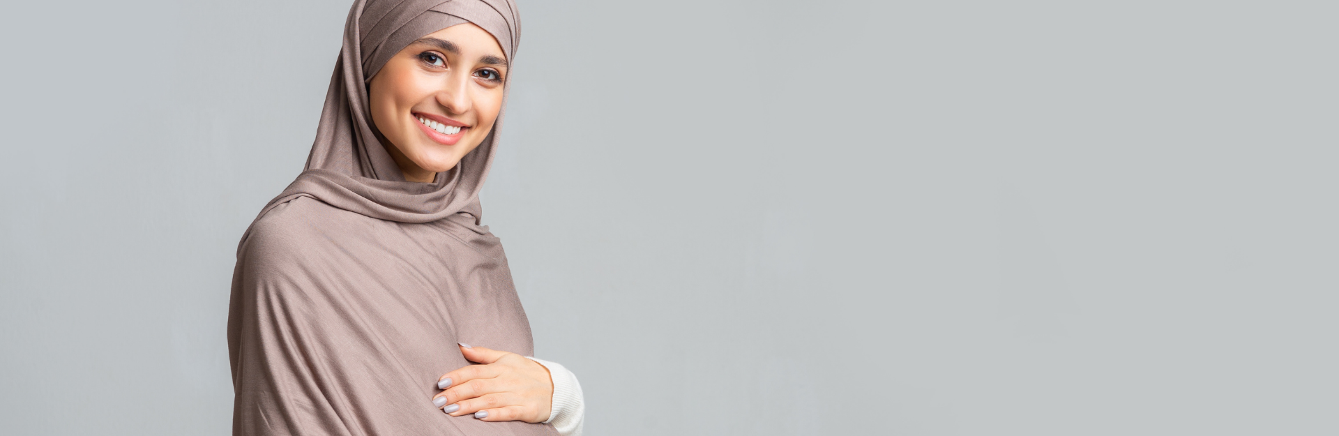 Smiling pregnant person with light brown hijab