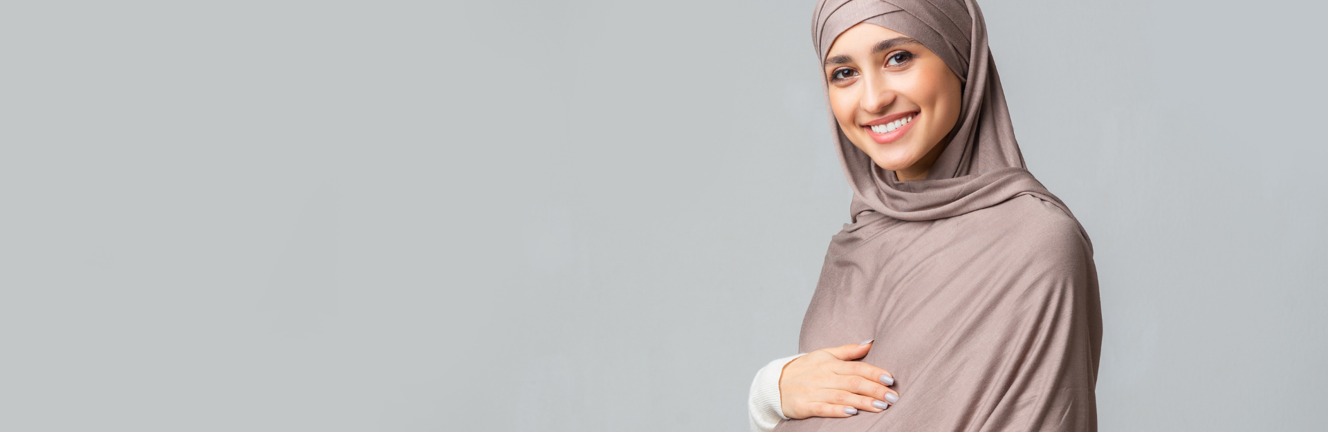 Smiling pregnant person with light brown hijab